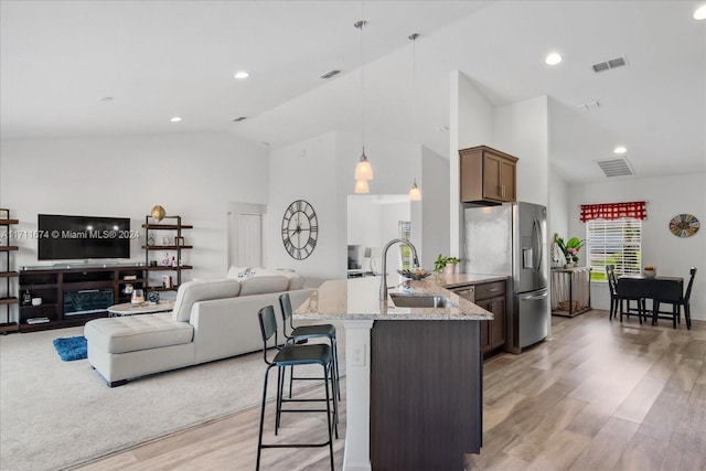 kitchen featuring stainless steel fridge with ice dispenser, light hardwood / wood-style flooring, pendant lighting, and light stone counters