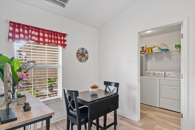 dining room with washing machine and dryer, light hardwood / wood-style flooring, and lofted ceiling