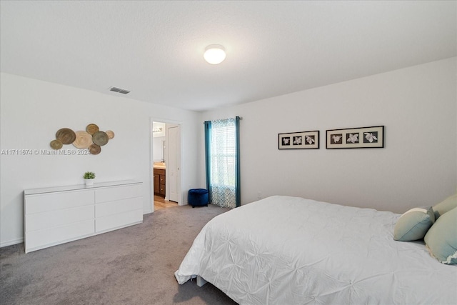 bedroom with connected bathroom and light carpet