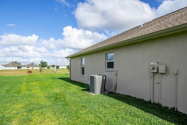 view of home's exterior with a lawn and central AC unit