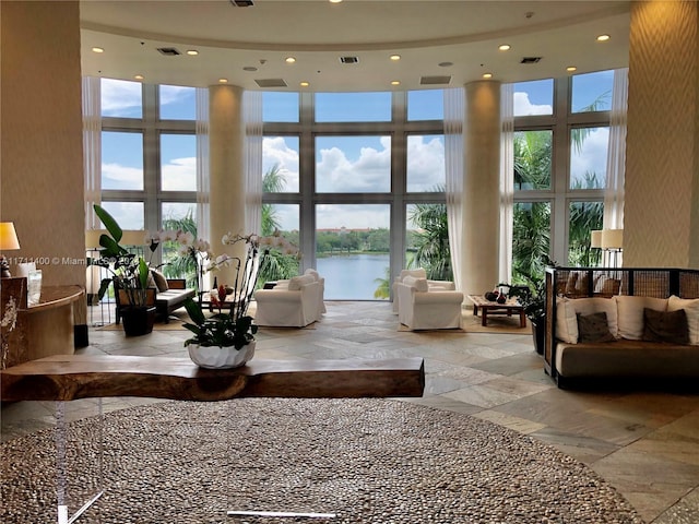 living room with expansive windows, a towering ceiling, and a water view