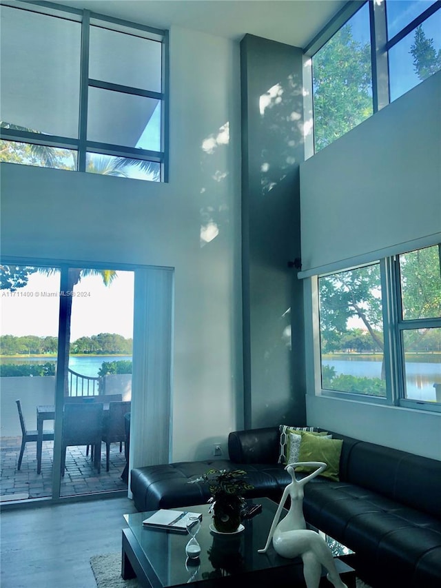 living room featuring a high ceiling, a water view, and wood-type flooring