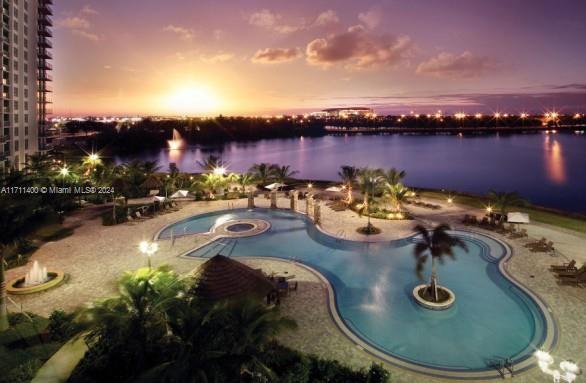 pool at dusk featuring a water view