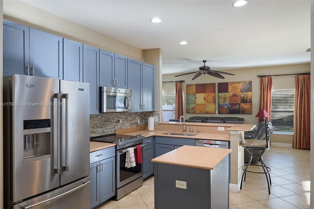 kitchen with a breakfast bar, sink, appliances with stainless steel finishes, a kitchen island, and a healthy amount of sunlight