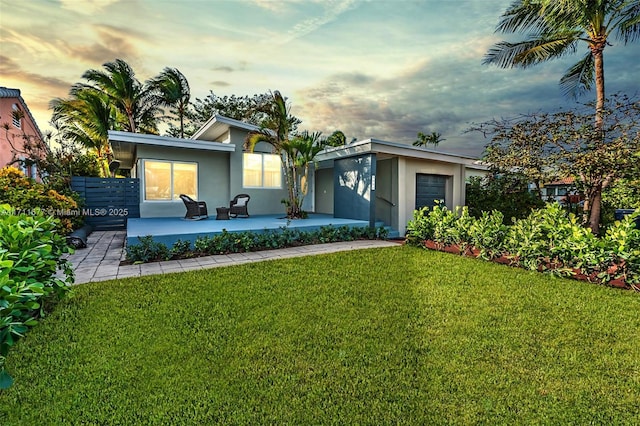 view of front of property with a patio area, stucco siding, and a lawn