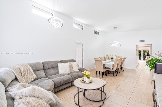 living area featuring visible vents, a notable chandelier, baseboards, and light tile patterned flooring