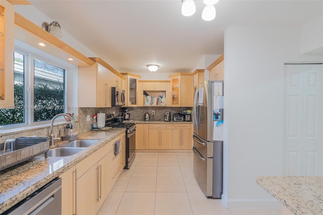 kitchen with light stone countertops, sink, light brown cabinets, decorative backsplash, and appliances with stainless steel finishes