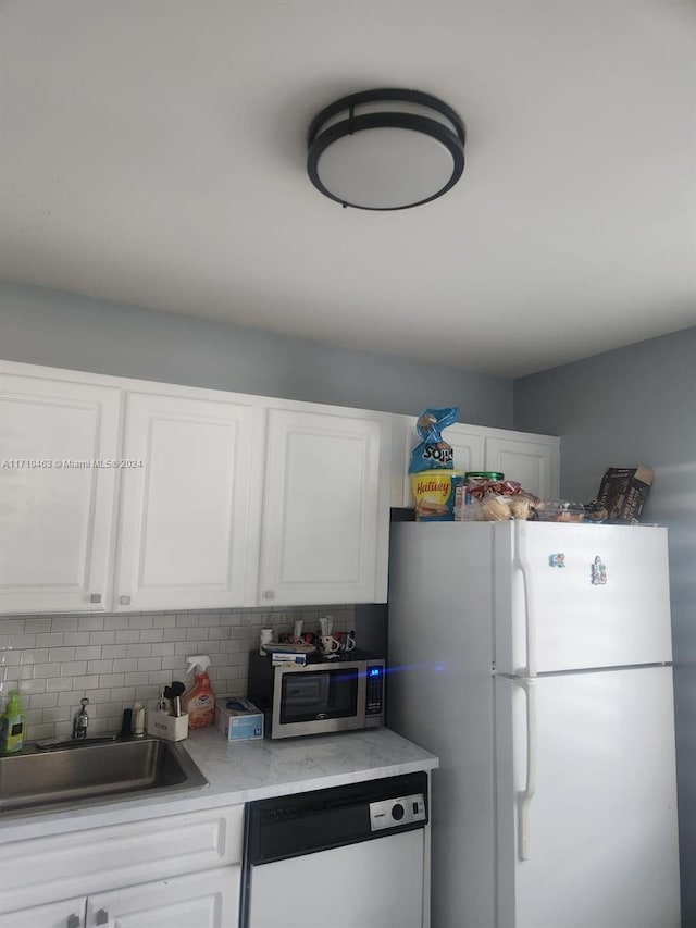 kitchen with tasteful backsplash, sink, white cabinets, and white appliances