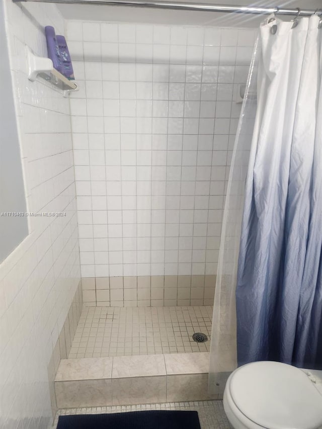 bathroom with tile patterned floors, toilet, tile walls, and a shower with shower curtain