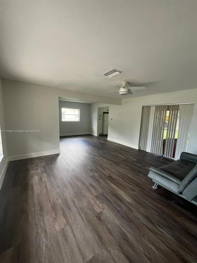 unfurnished living room with dark hardwood / wood-style flooring and ceiling fan