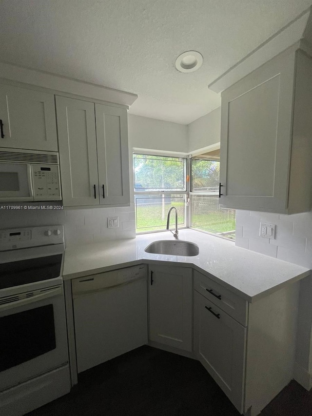 kitchen featuring decorative backsplash, white cabinetry, sink, and white appliances