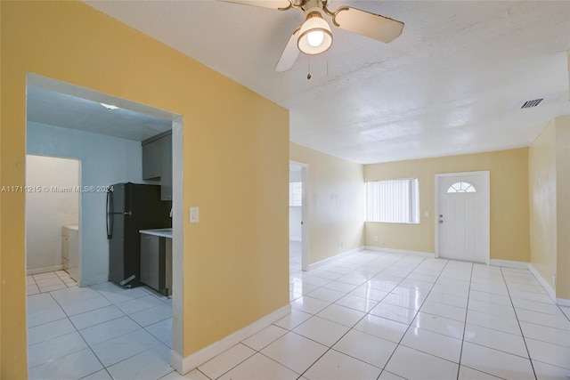 foyer featuring ceiling fan, light tile patterned floors, and a textured ceiling