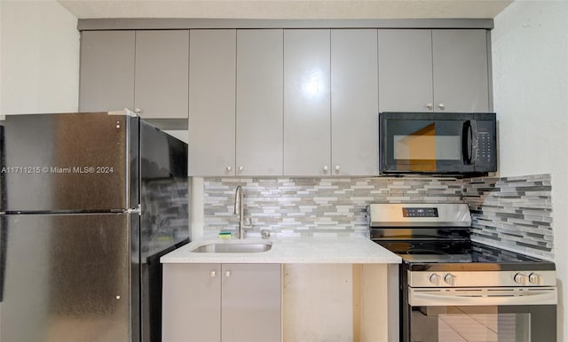 kitchen featuring stainless steel range with electric cooktop, fridge, sink, gray cabinets, and tasteful backsplash