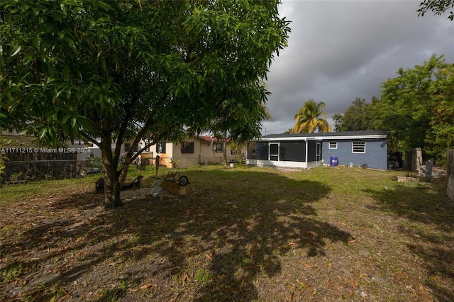 back of house featuring a sunroom and a lawn