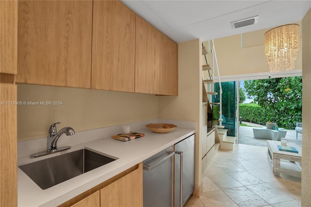 kitchen featuring light brown cabinetry, sink, stainless steel refrigerator, and a chandelier