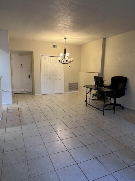 living area with a chandelier, light tile patterned floors, and a textured ceiling