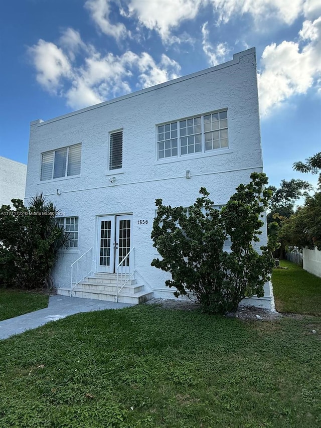 back of property featuring french doors and a lawn