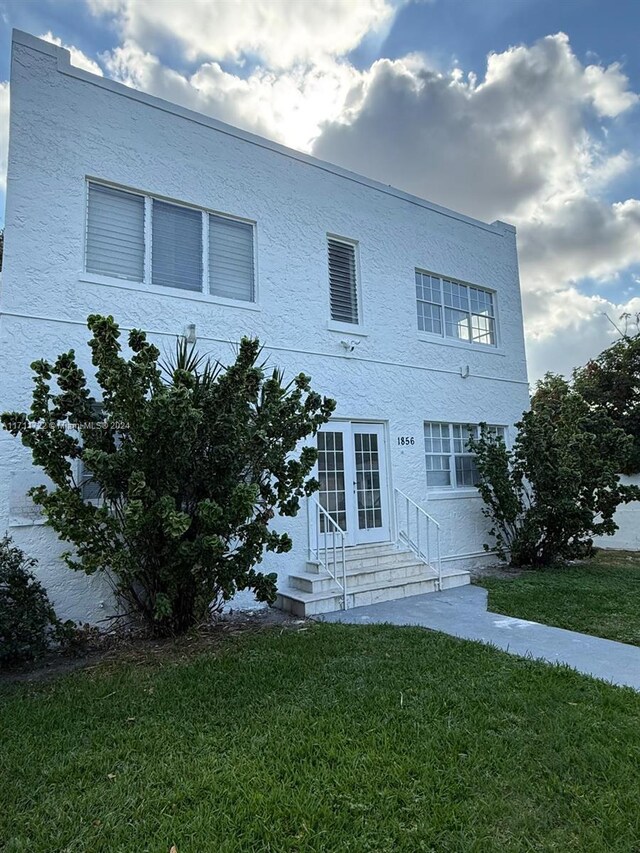 view of front of house with french doors and a front lawn