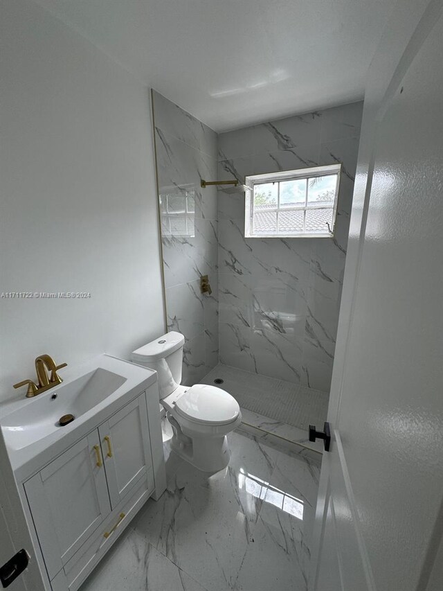 bathroom featuring tiled shower, vanity, and toilet