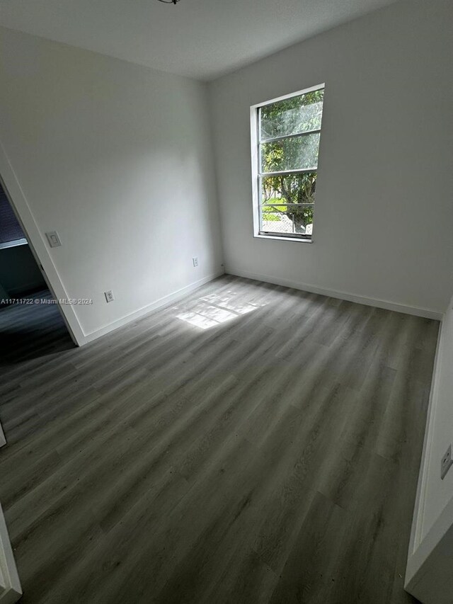 unfurnished room featuring dark wood-type flooring