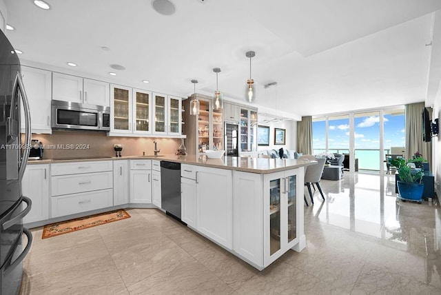 kitchen featuring floor to ceiling windows, white cabinetry, stainless steel appliances, and decorative light fixtures