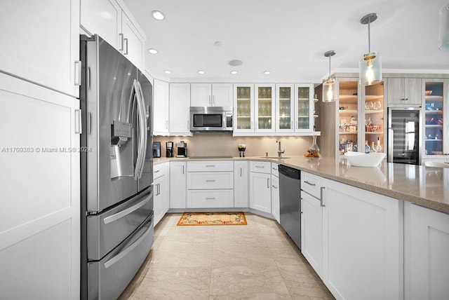 kitchen with light stone countertops, pendant lighting, stainless steel appliances, and white cabinetry