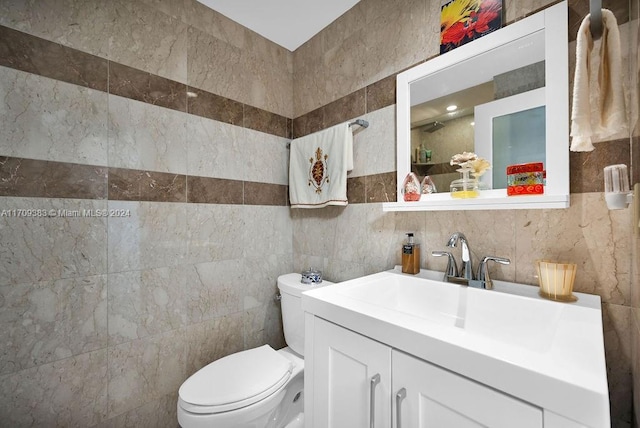 bathroom featuring vanity, toilet, and tile walls