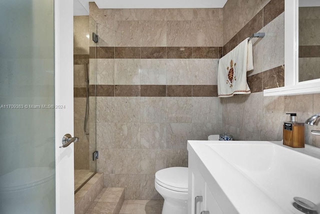 bathroom with vanity, toilet, a shower with door, and tile walls