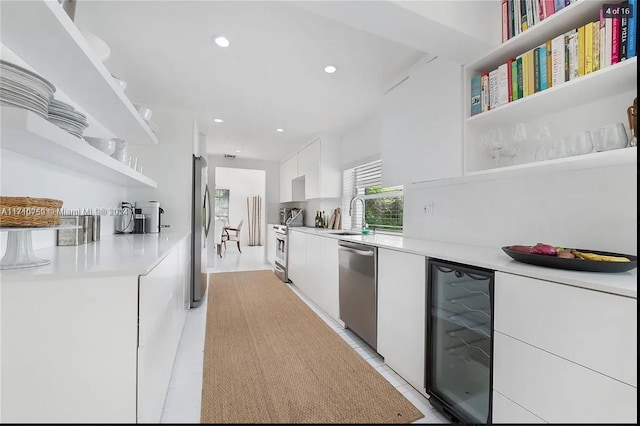 kitchen with white cabinetry, sink, beverage cooler, stainless steel appliances, and light tile patterned flooring