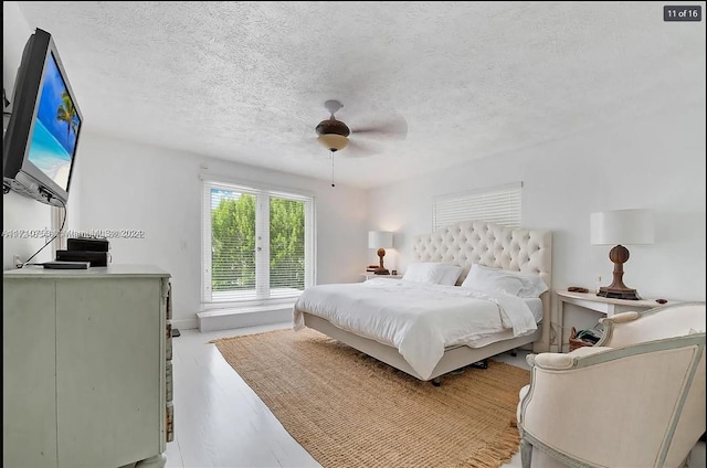 bedroom featuring ceiling fan, light hardwood / wood-style flooring, and a textured ceiling