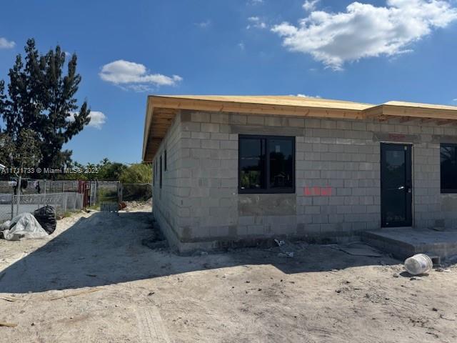 view of side of property with concrete block siding and fence