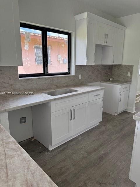 kitchen with dark wood-style flooring, tasteful backsplash, light countertops, and white cabinets
