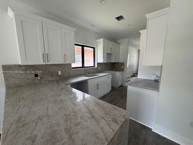 kitchen featuring dark wood finished floors, tasteful backsplash, light stone countertops, white cabinets, and visible vents