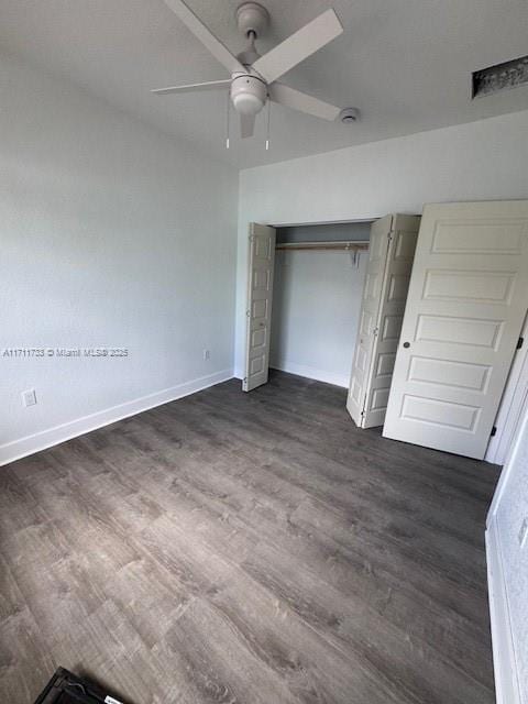 unfurnished bedroom with baseboards, a ceiling fan, a closet, and dark wood-type flooring