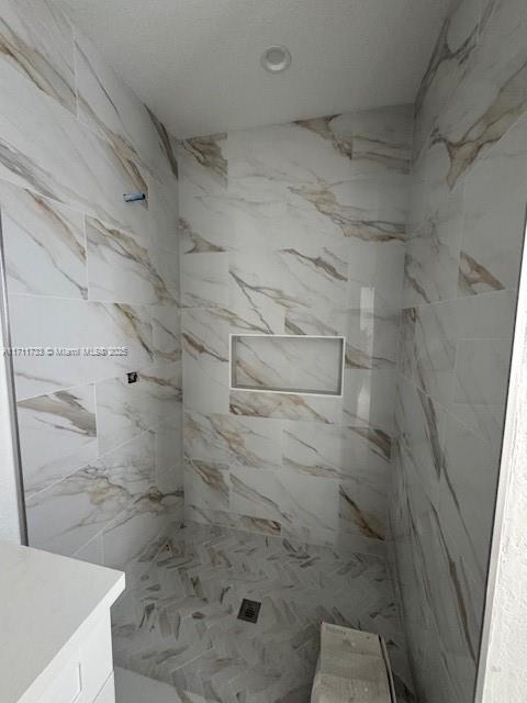 bathroom featuring vanity and a marble finish shower