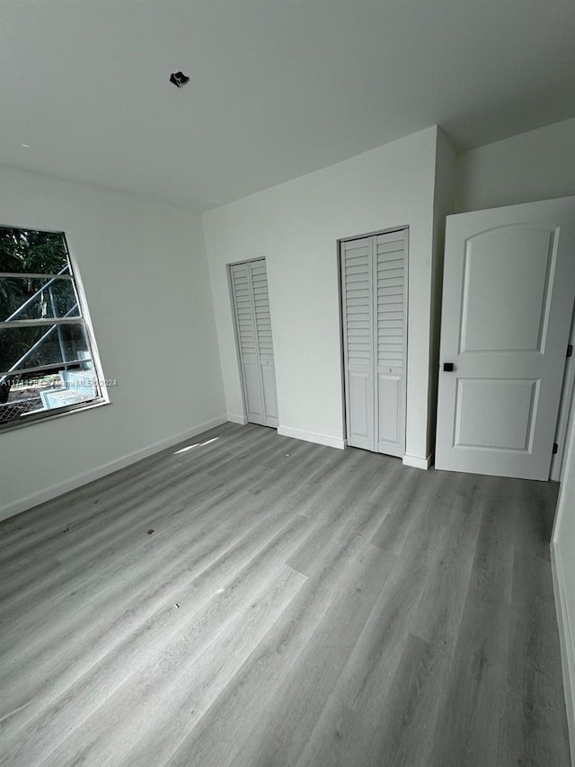 unfurnished bedroom featuring two closets and light wood-type flooring