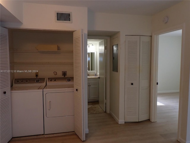 laundry area featuring independent washer and dryer, light wood-type flooring, and electric panel