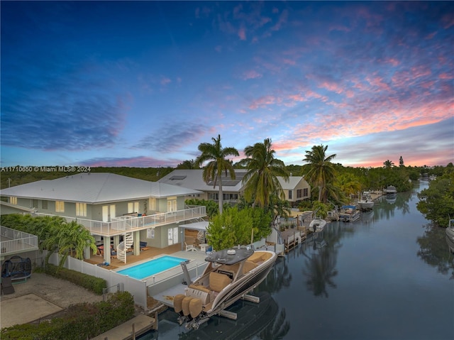 back house at dusk featuring a patio, a water view, and a balcony