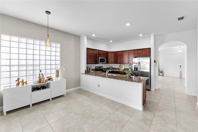 kitchen featuring stainless steel appliances, sink, light tile patterned floors, dark stone countertops, and hanging light fixtures