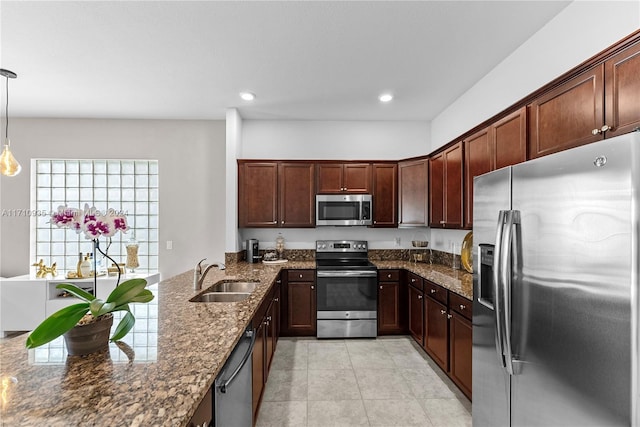 kitchen featuring dark stone counters, sink, hanging light fixtures, light tile patterned floors, and appliances with stainless steel finishes