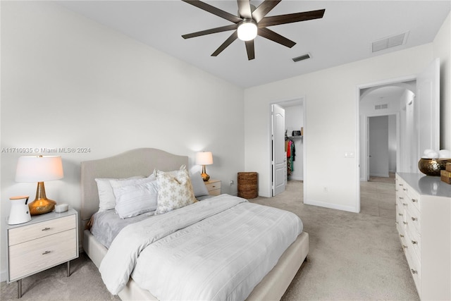 carpeted bedroom featuring a walk in closet, ceiling fan, and a closet