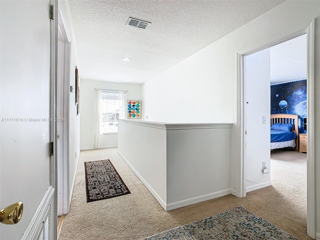 hall featuring light colored carpet and a textured ceiling