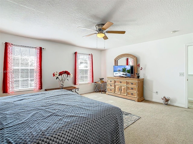 bedroom featuring carpet flooring, multiple windows, ceiling fan, and a textured ceiling