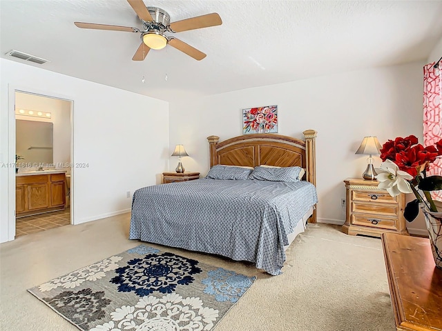 carpeted bedroom with a textured ceiling, ensuite bathroom, and ceiling fan