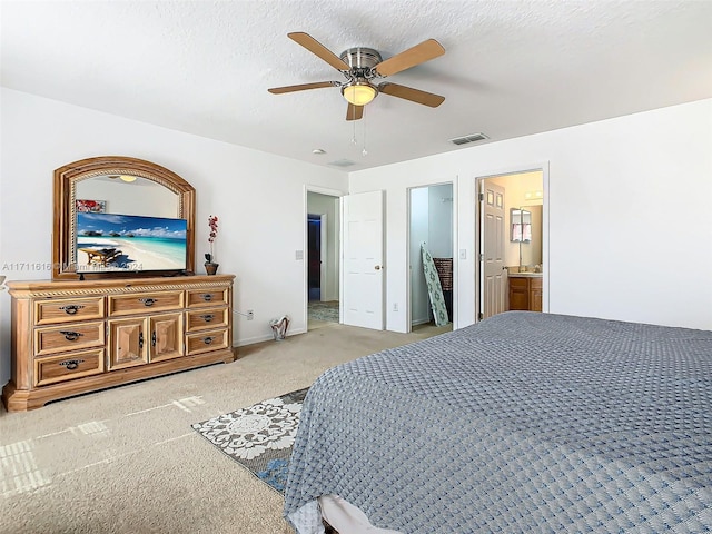 carpeted bedroom with a textured ceiling, connected bathroom, and ceiling fan