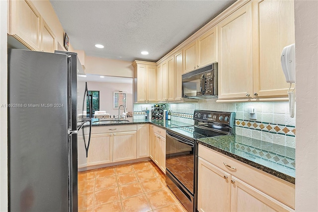 kitchen with black appliances, decorative backsplash, sink, and dark stone counters