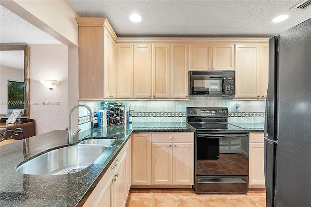 kitchen with sink, dark stone counters, decorative backsplash, light tile patterned floors, and black appliances