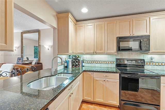 kitchen with a textured ceiling, electric range, dark stone countertops, and sink