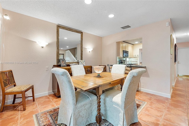 tiled dining space featuring a textured ceiling