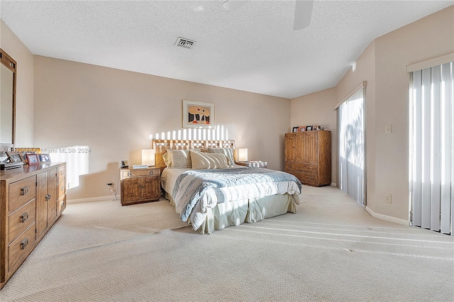 carpeted bedroom featuring ceiling fan and a textured ceiling